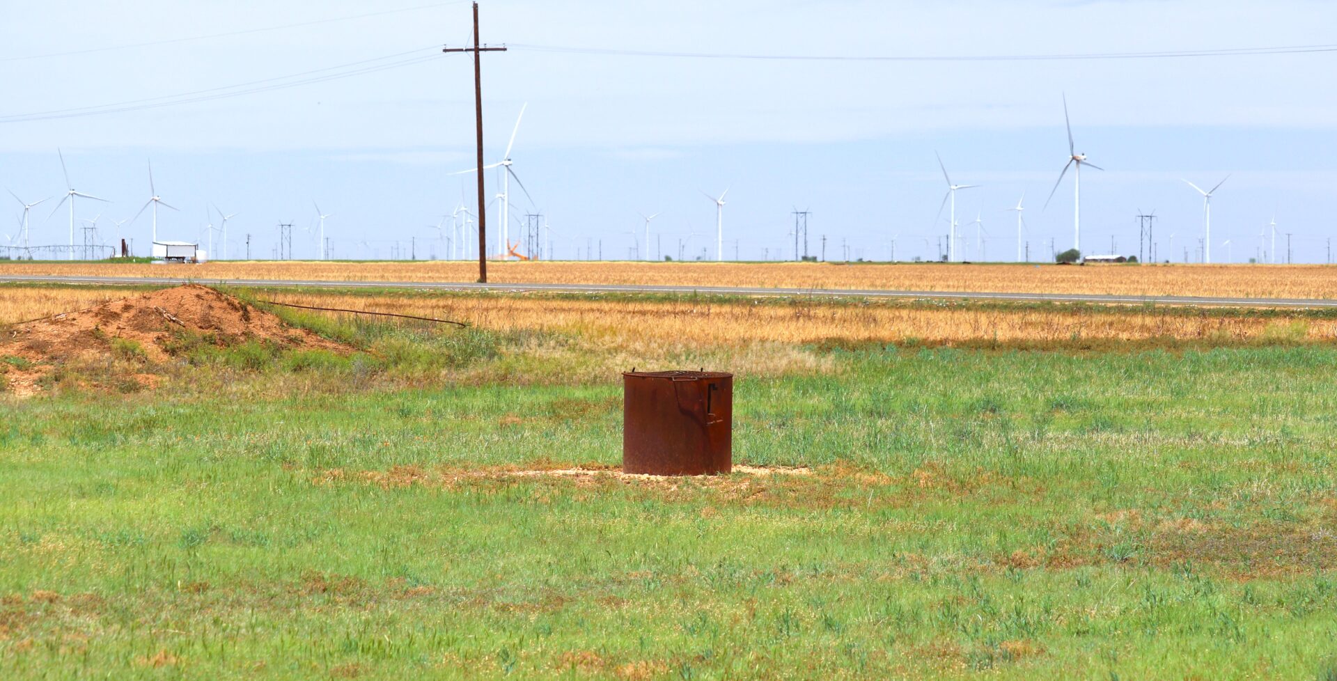Rusty metal container in grassy field.