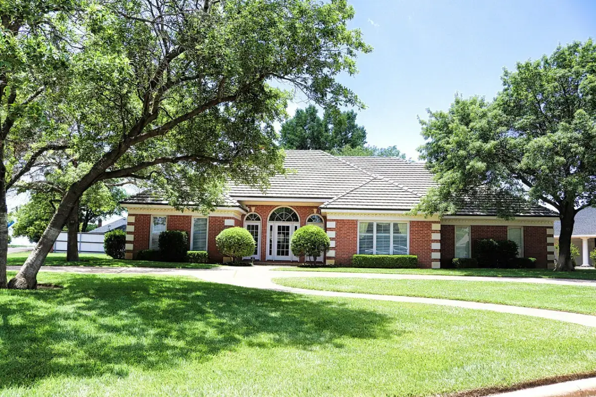 Brick house with trees and green lawn.